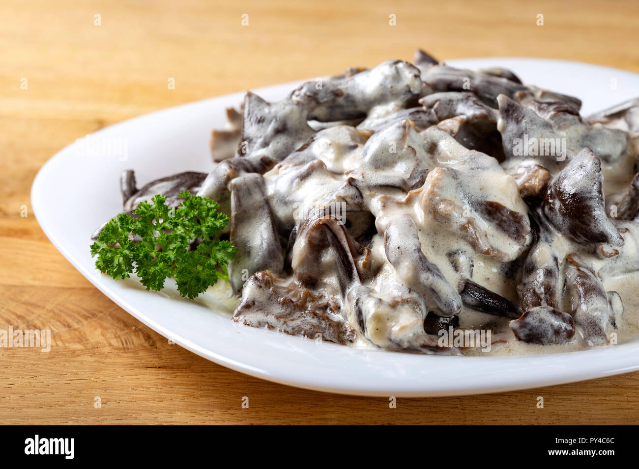 Stufato preparato da funghi marrone e panna acida e erbe su piastra Foto Stock