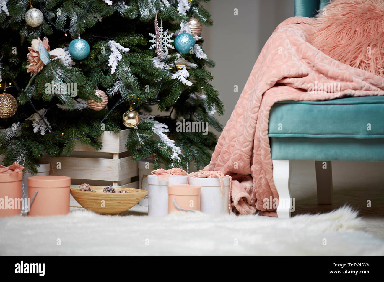 Poltrona con coperta in prossimità di albero di Natale e regali Foto Stock