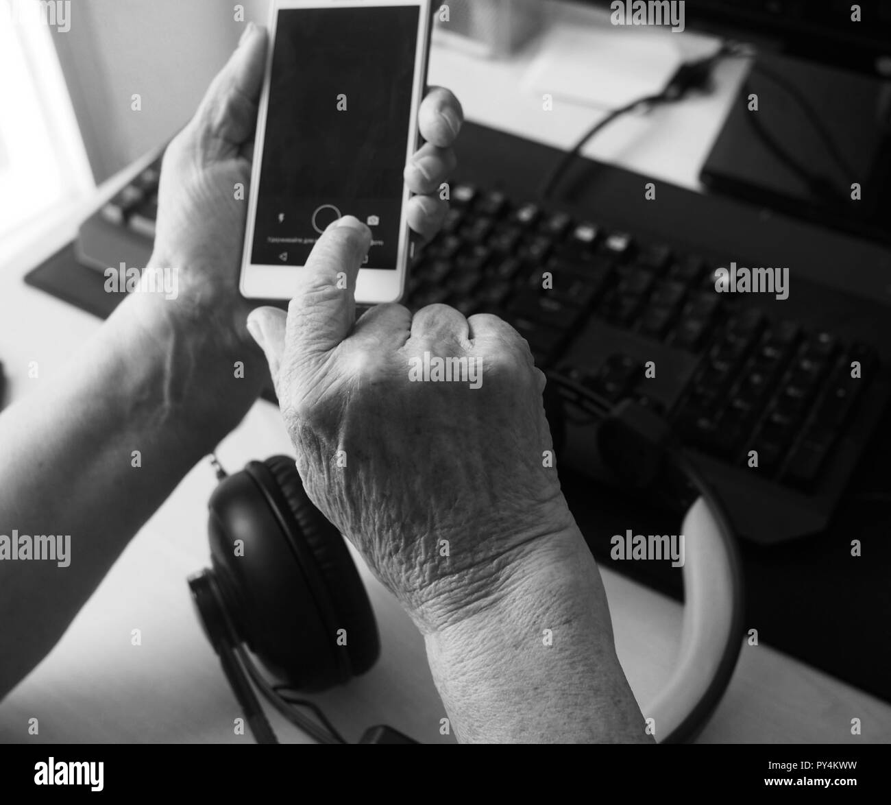 Il vecchio donna smartphone tiene nelle sue mani. Donna anziana guardando uno smart phone dentro la sua casa Foto Stock