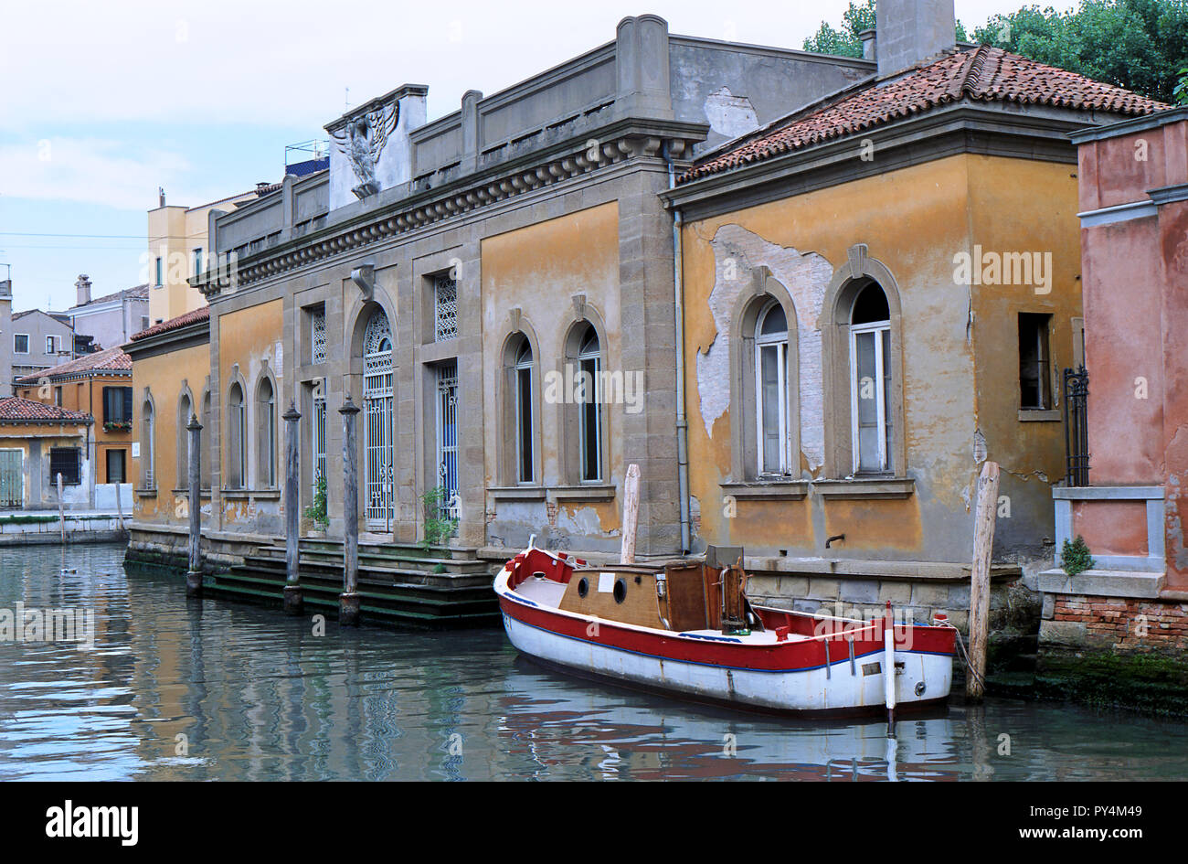 Barca ormeggiata presso un vecchio palazzo di Venezia con ampia repairwork visibili sulle pareti, Italia Foto Stock