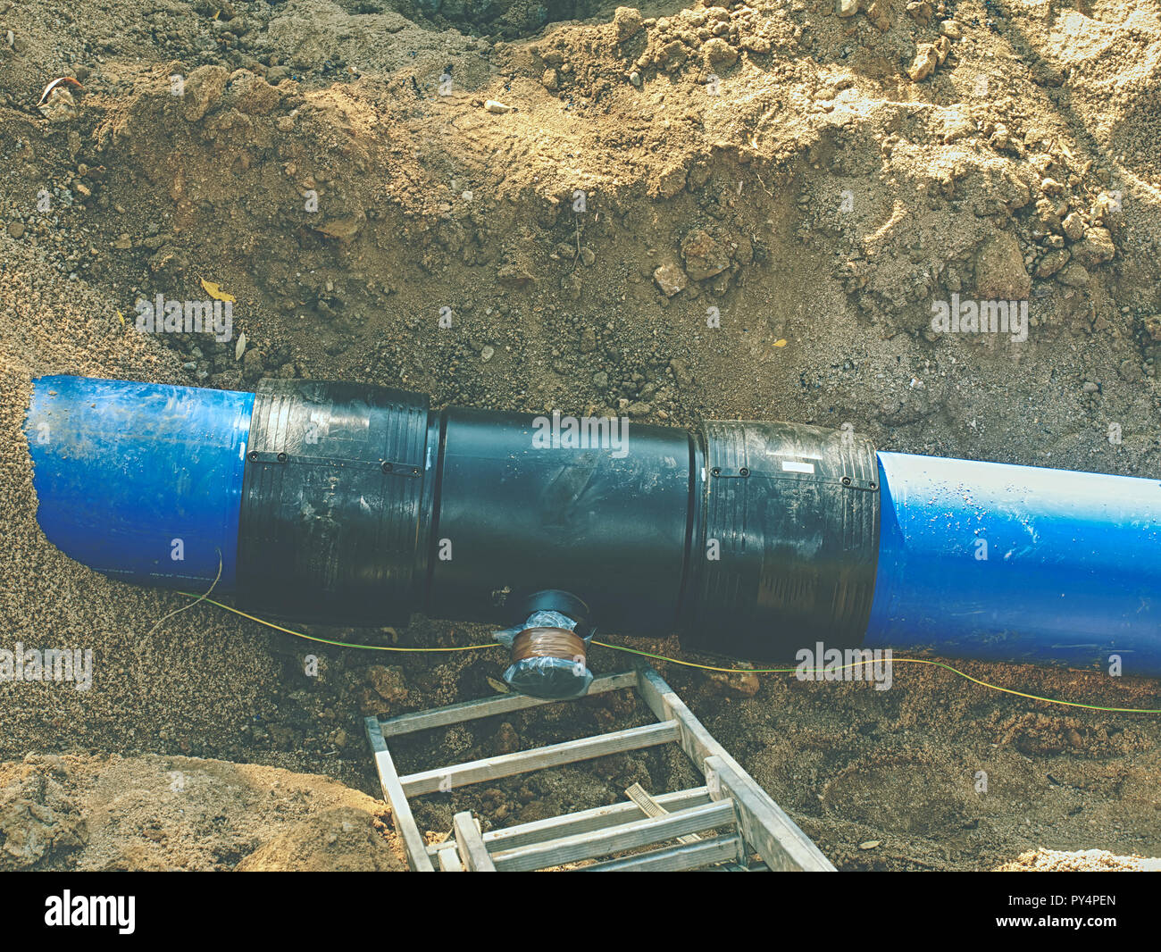 Scavo per la posa di una tubazione di alimentazione dell'acqua. Costruzione  di tubature per acqua potabile con gate in shallow trench Foto stock - Alamy