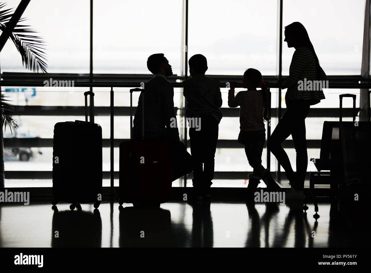 La famiglia attende per il volo in vacanza con la mia famiglia a sosta nel terminal dell'aeroporto Foto Stock