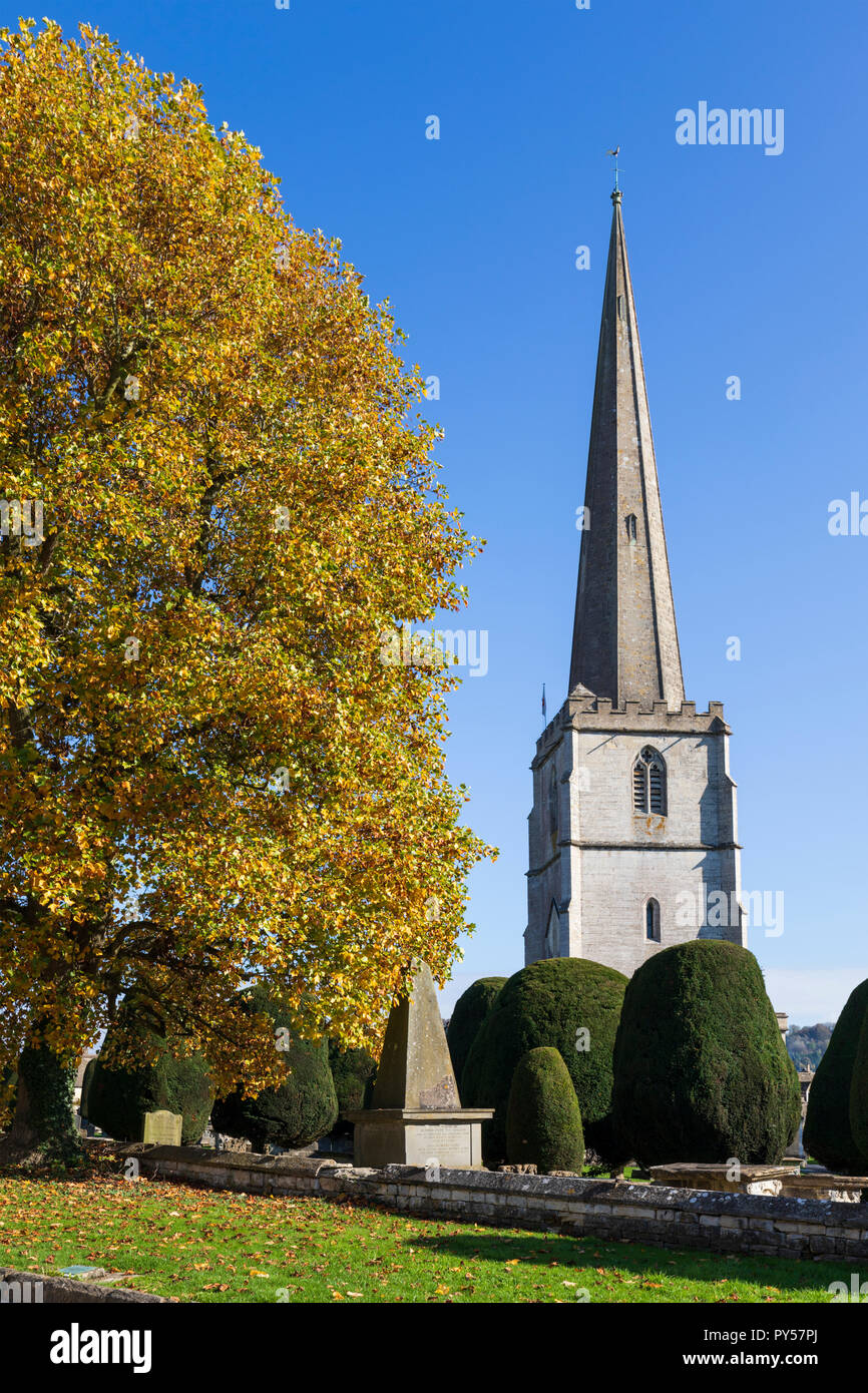 Painswick St Mary's chiesa parrocchiale con colori autunnali albero nel pomeriggio di sole, Painswick, Cotswolds, Gloucestershire, England, Regno Unito Foto Stock