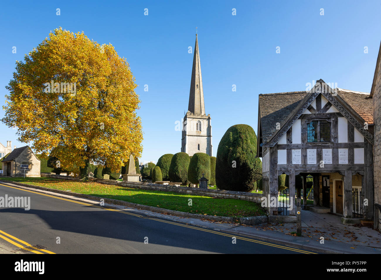 Painswick St Mary's chiesa parrocchiale e lychgate con colori autunnali albero nel pomeriggio di sole, Painswick, Cotswolds, Gloucestershire, England, Regno Unito Foto Stock