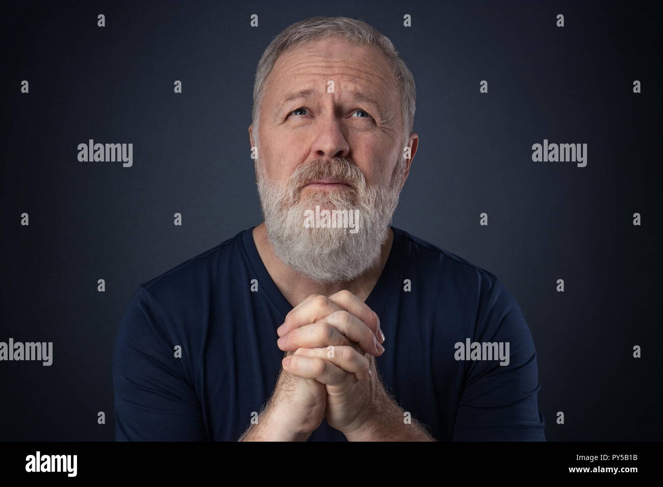 Uomo anziano con barba grigia a pregare con le mani insieme Foto Stock