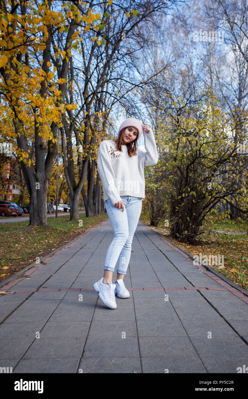 Moda giovane donna hipstaer nel casual abbigliamento stagionale Caldo  cappello e jeans blu oltre urbano per la città di sfondo ritratto  d'autunno. Hipster ragazza in posa a str Foto stock - Alamy