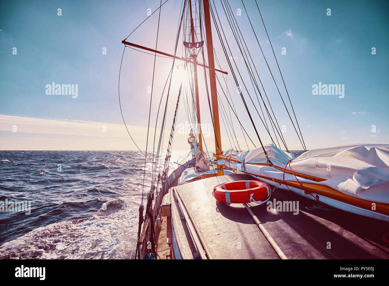Barca a vela contro il sole, viaggi e avventura concetto, dai toni di colore dell'immagine. Foto Stock