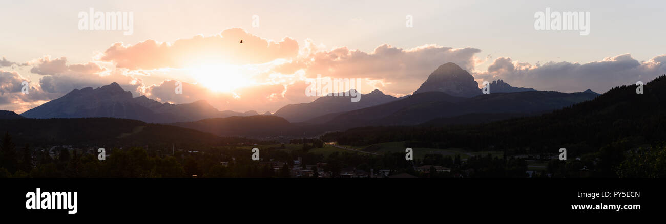 Sun picchi fuori da dietro le nuvole sopra Crowsnest Mountain e sette sorelle Mountain Foto Stock