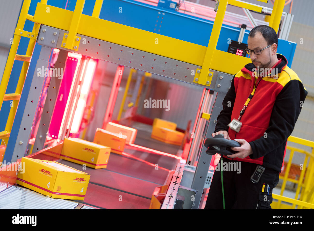 Klipphausen, Germania. 25 ott 2018. Dipendente Manuel Kunze supervisiona il trasporto di colli sul nastro in corrispondenza della apertura della nuova DHL Express posizione logistica. Nell'area di movimentazione con completamente automatico sistema di smistamento, 3000 spole per ora può essere elaborato. Credito: Monika Skolimowska/dpa-Zentralbild/ZB/dpa/Alamy Live News Foto Stock