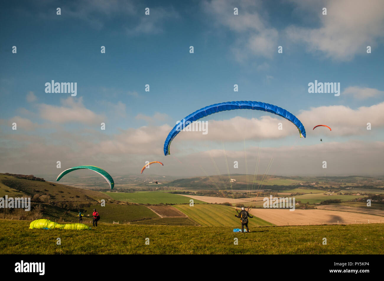 Firle, Lewes, East Sussex, Regno Unito. 25 ottobre 2018..un vento freddo dal Nord porta piloti di parapendio a Firle Beacon nella bella South Downs. Foto Stock