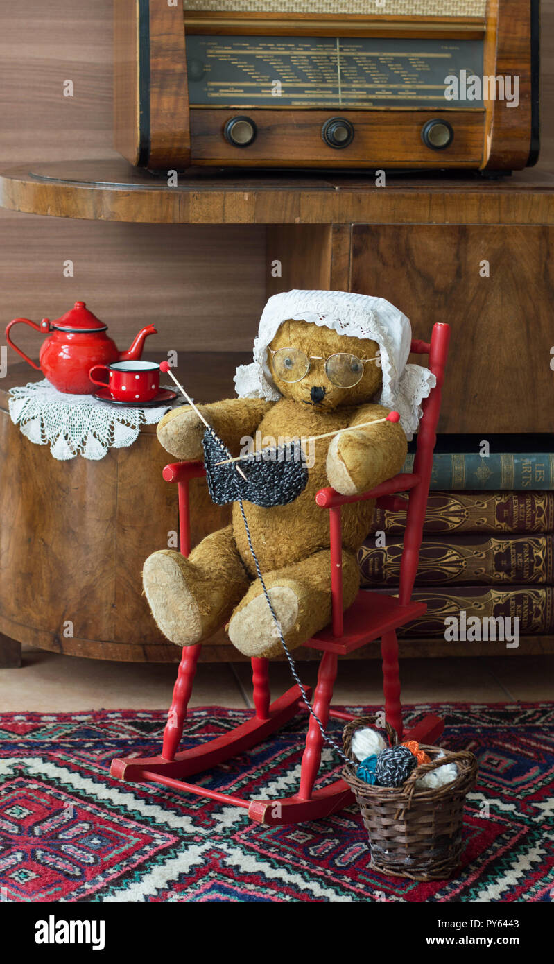 Orsacchiotto di peluche nonna maglia in una sedia a dondolo in un vintage interno Foto Stock