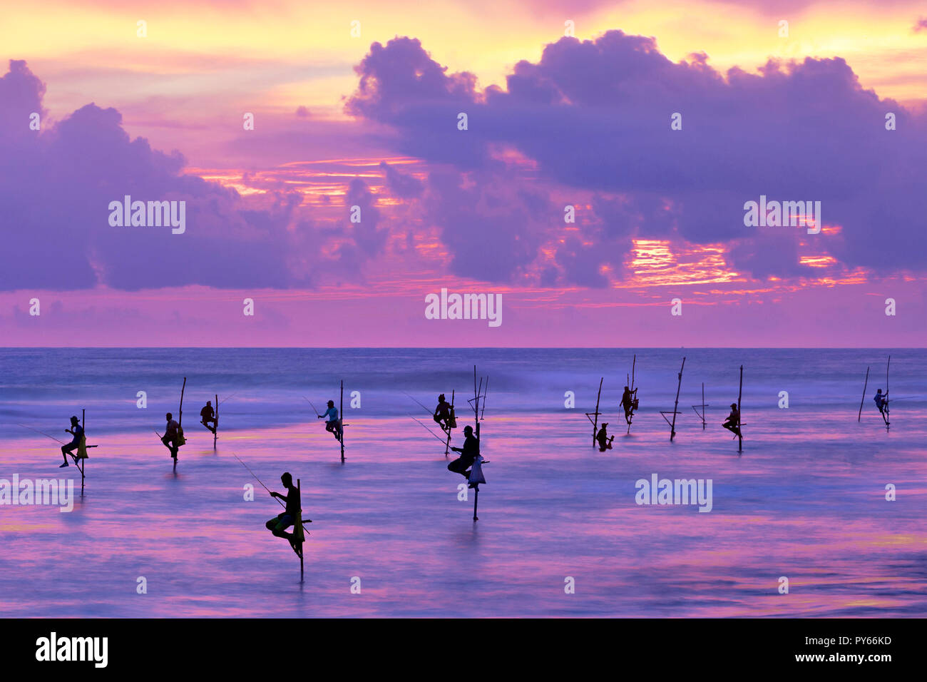 I pescatori su palafitte in silhouette al tramonto a Galle, Sri Lanka Foto Stock