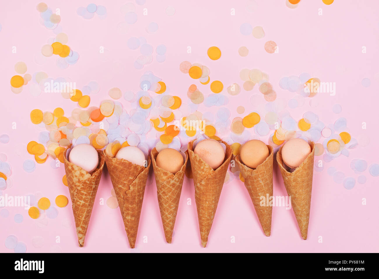 Gelato coni di cialda con macarons e coriandoli colorati su sfondo rosa. Colorati e pastello colori caramella. Dolci. Foto Stock