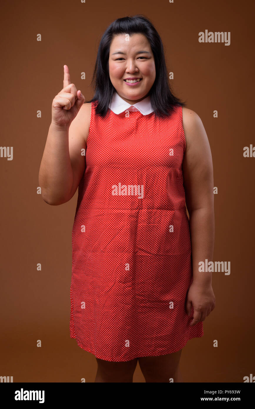 Bellissimo il sovrappeso donna asiatica sorridente e puntare il dito fino Foto Stock