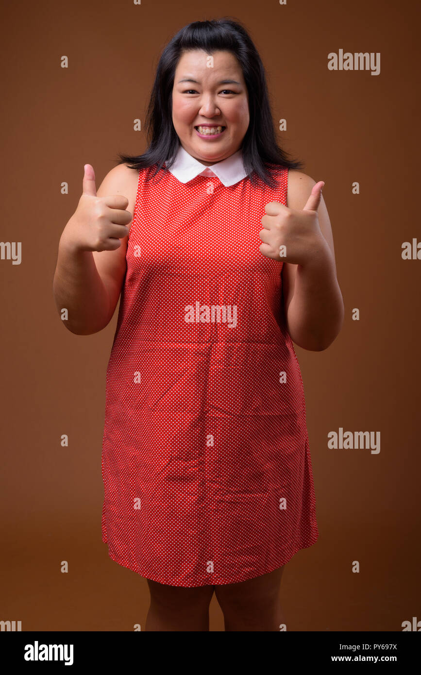 Bella felice sovrappeso donna asiatica dando pollice in alto Foto Stock