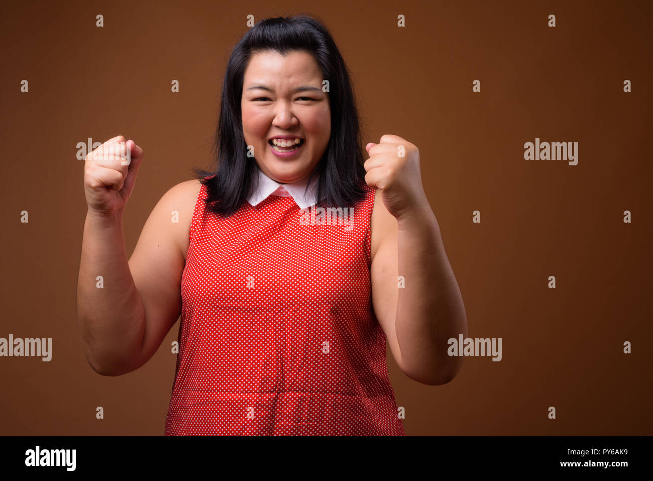 Bella felice sovrappeso donna asiatica a braccia alzate Foto Stock