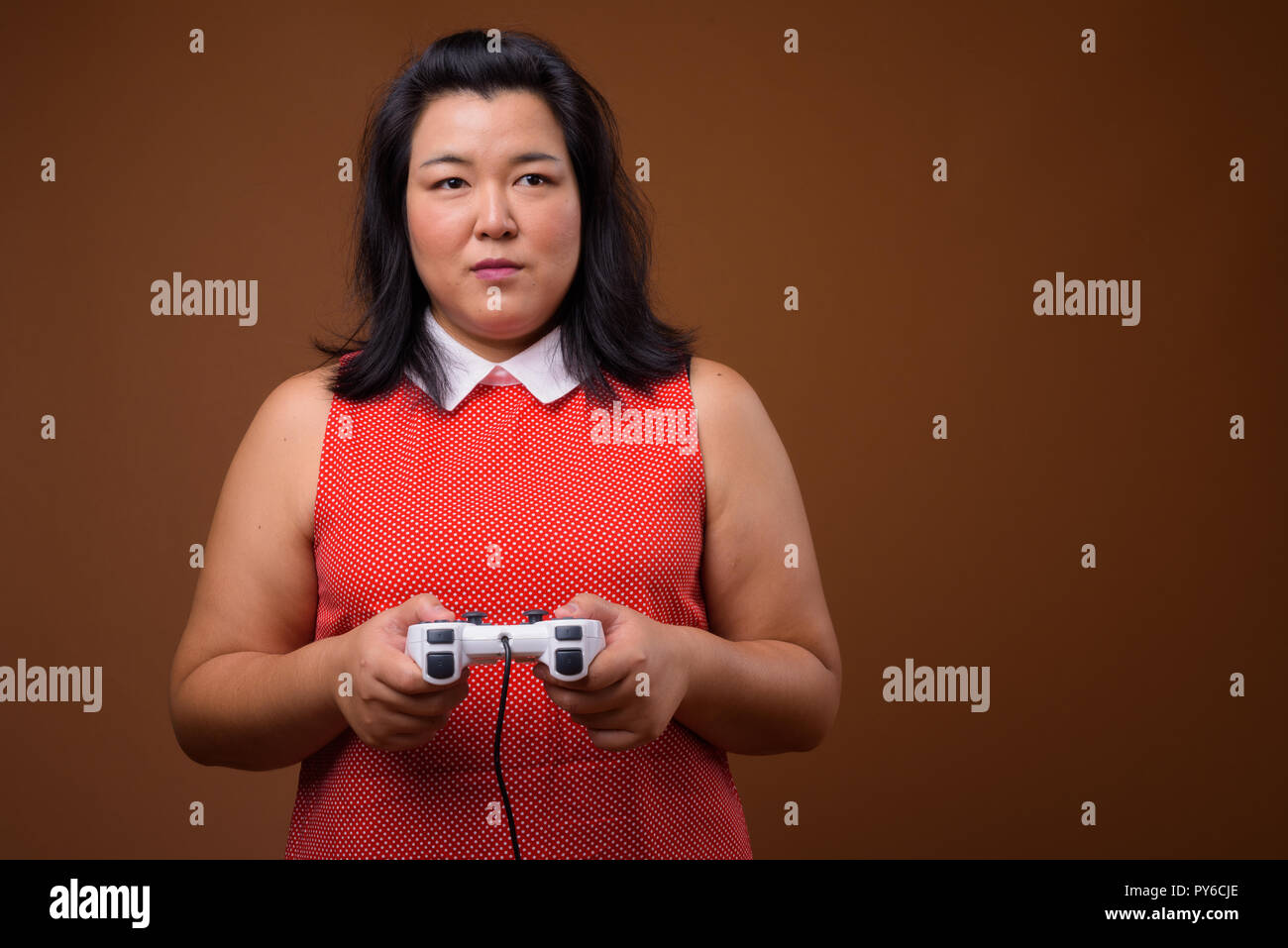 Bellissimo il sovrappeso donna asiatica riproduzione di video giochi utilizzando il controller di gioco Foto Stock