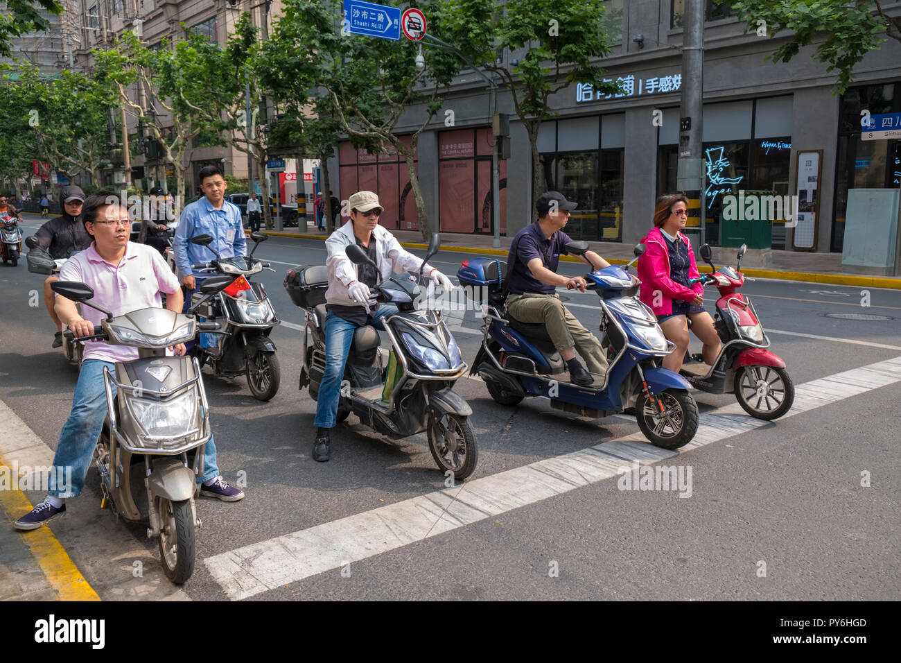 Gruppo di persone a cavallo degli scooter in una strada a Shanghai in Cina, Asia Foto Stock