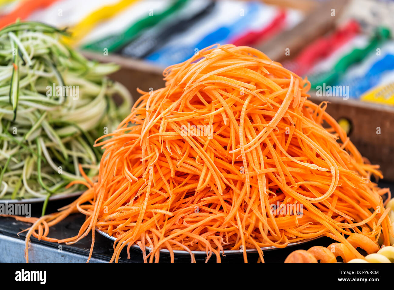 Closeup pila di molti shredded carote, zucchine e cetrioli di tagliolini crudi spiralizzato materie la cottura di preparazione in outdoor street cibo sano mercato, oran Foto Stock