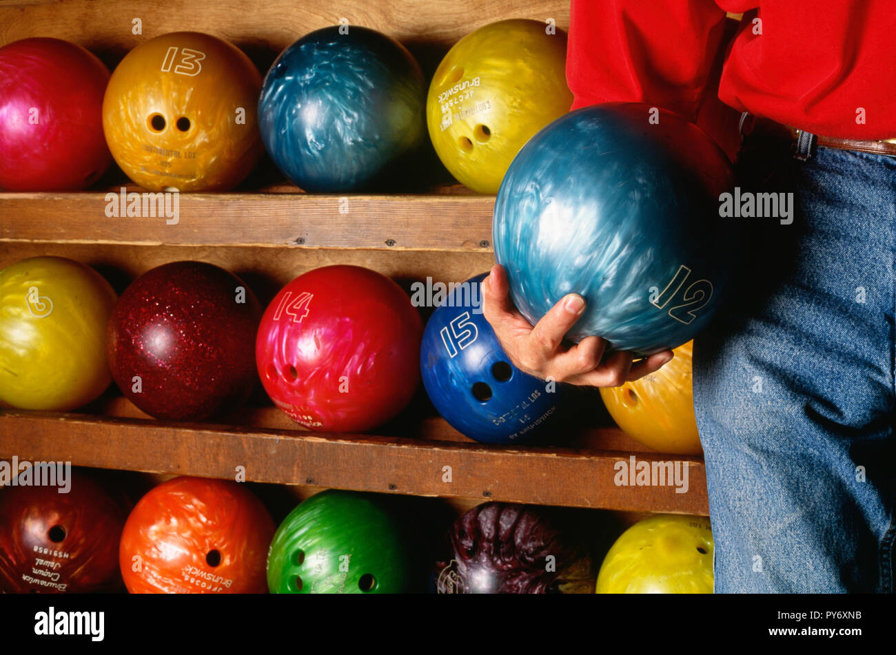 L'uomo tiene palla da bowling nella parte anteriore del rack a sfera, STATI UNITI D'AMERICA Foto Stock