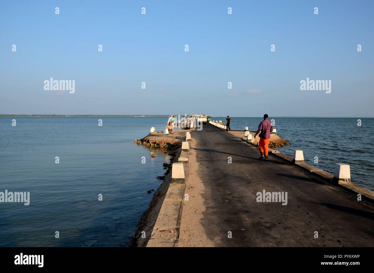 Gli abitanti dello Sri Lanka a piedi su un causeway road verso un pontile in acqua Jaffna nello Sri Lanka Foto Stock