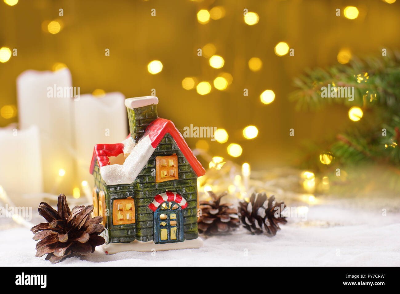 Decorazione del nuovo anno la tabella nella forma di una casa di argilla, candele bianche con ghirlande di spumante su un sfondo dorato. Foto Stock