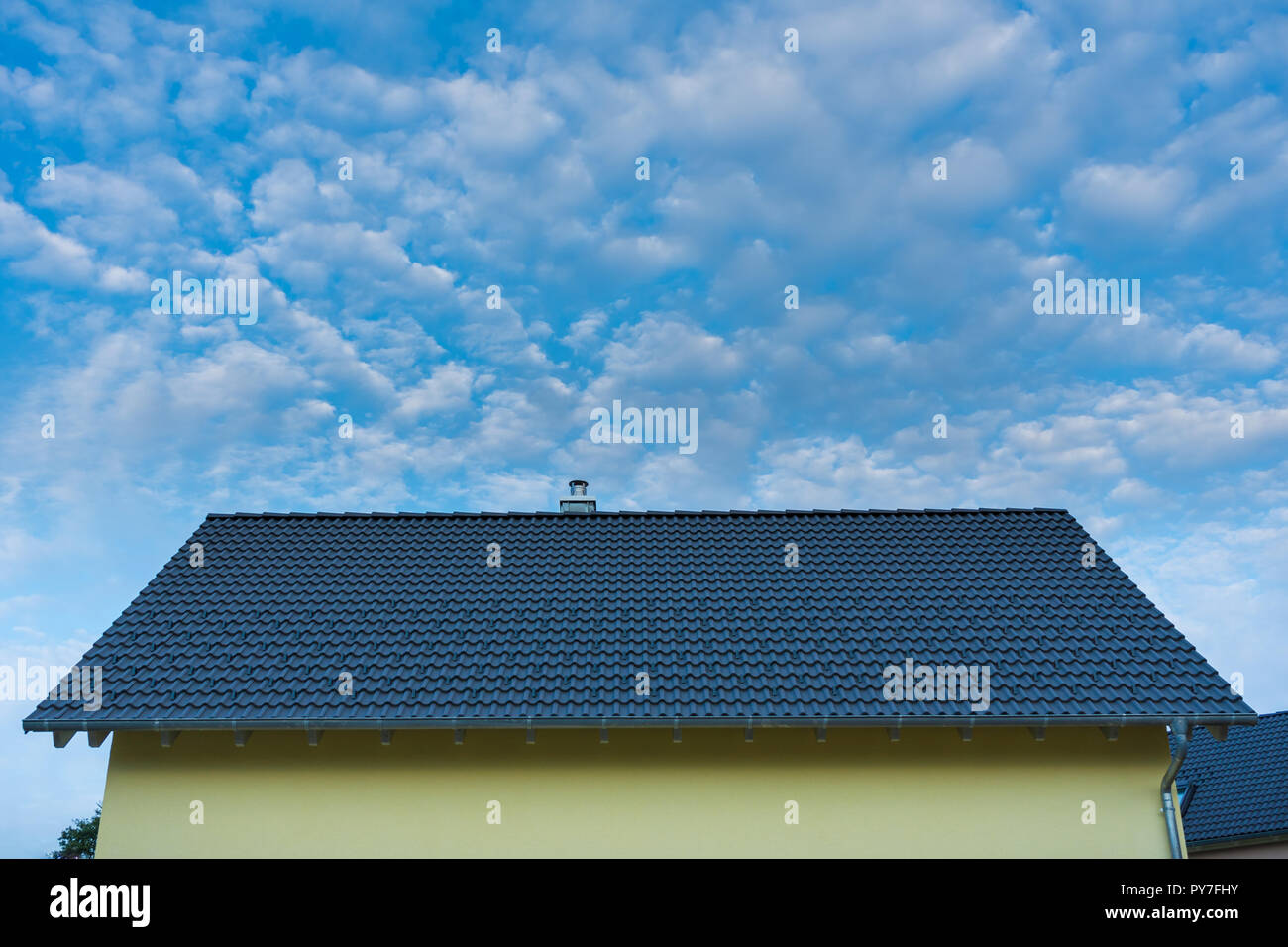 Giallo casa nuova e tetto in tegole del tetto con il blu del cielo Foto Stock