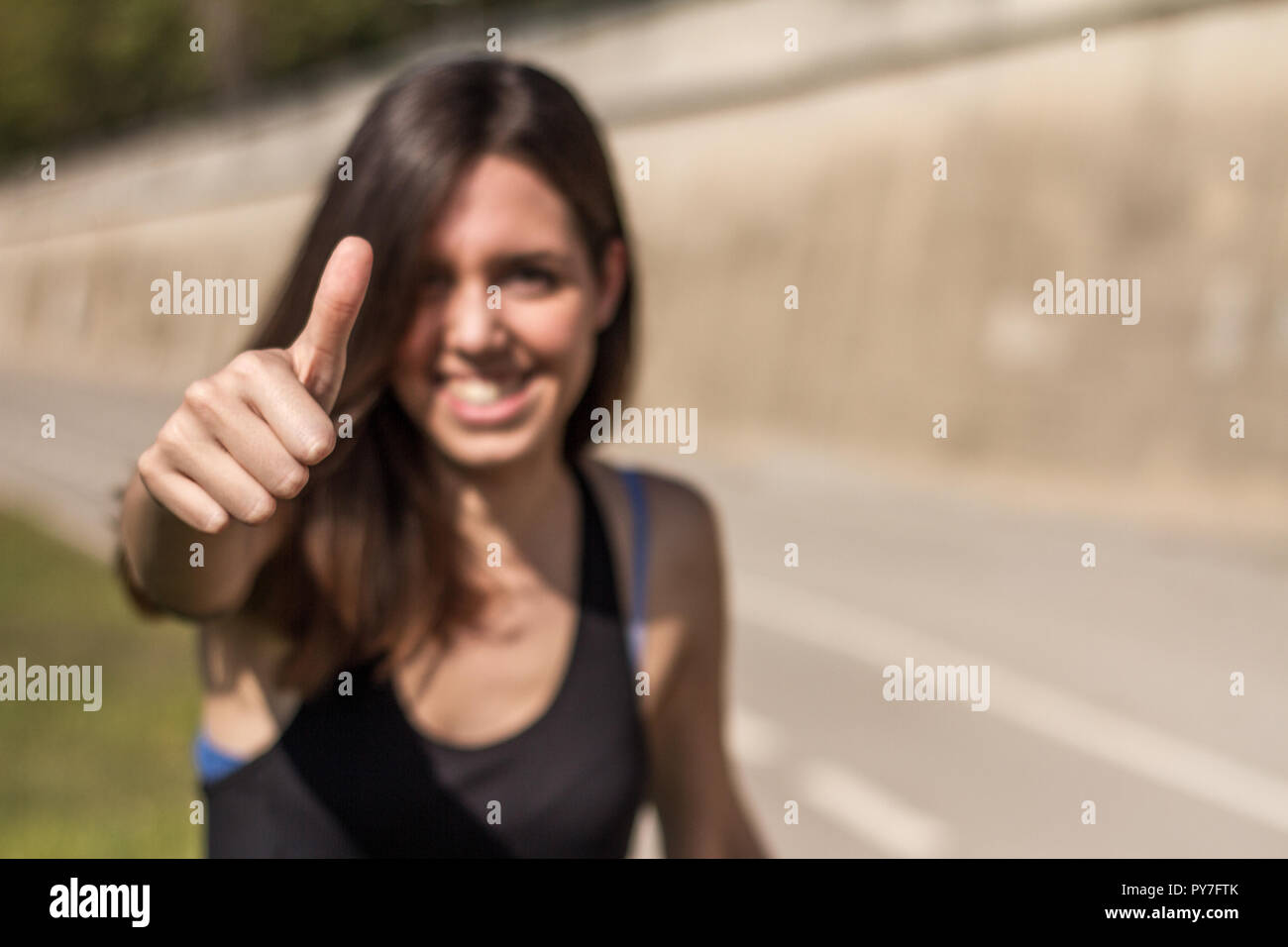 Sorridenti montare donna con segno OK con la mano, mostrando i pollici fino al gesto fotocamera, espressione di simili e approvazione e ok okey in strada molto felice Foto Stock