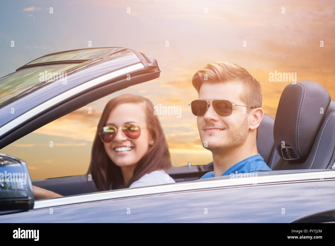 Coppia giovane indossando occhiali da sole godendo fate un giro in auto Foto Stock