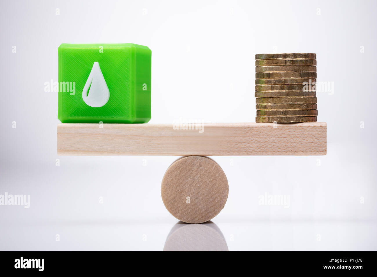 Verde Blocco cubico con icona Waterdrop e monete impilate in equilibrio su altalena in legno Foto Stock