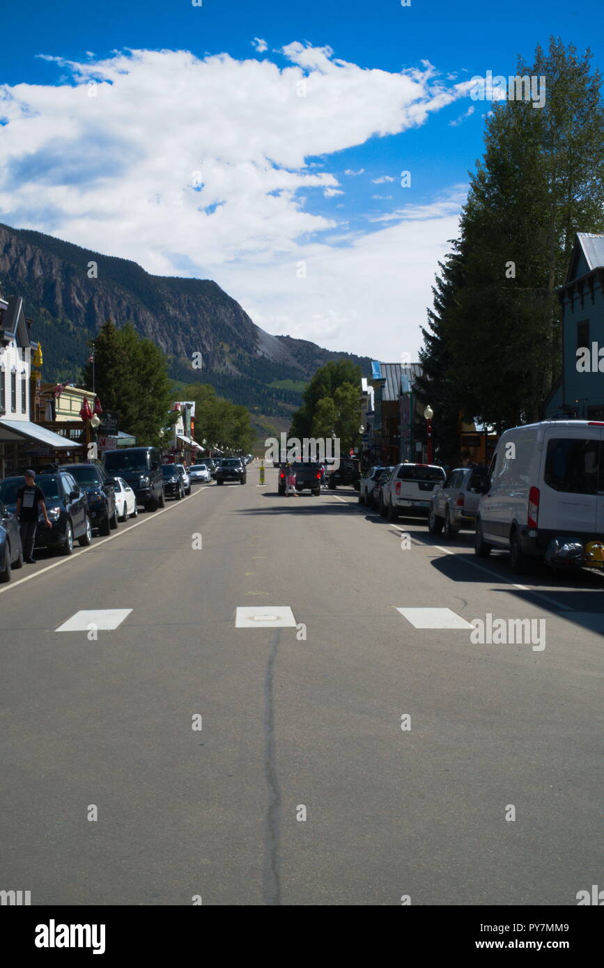 La strada principale di Crested Butte Colorado. Vi è un crosswalk, persone, automobili parcheggiate sul lato, alberi, edifici ed un cielo blu. Foto Stock