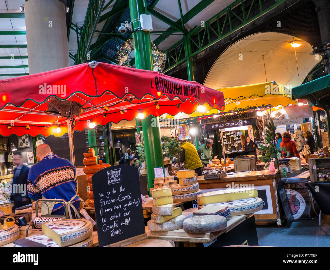 Formaggio Natale Borough Market accese le bancarelle del mercato degustazione di formaggi si spegne a tarda notte shopping invernale con campioni Southwark Londra Foto Stock