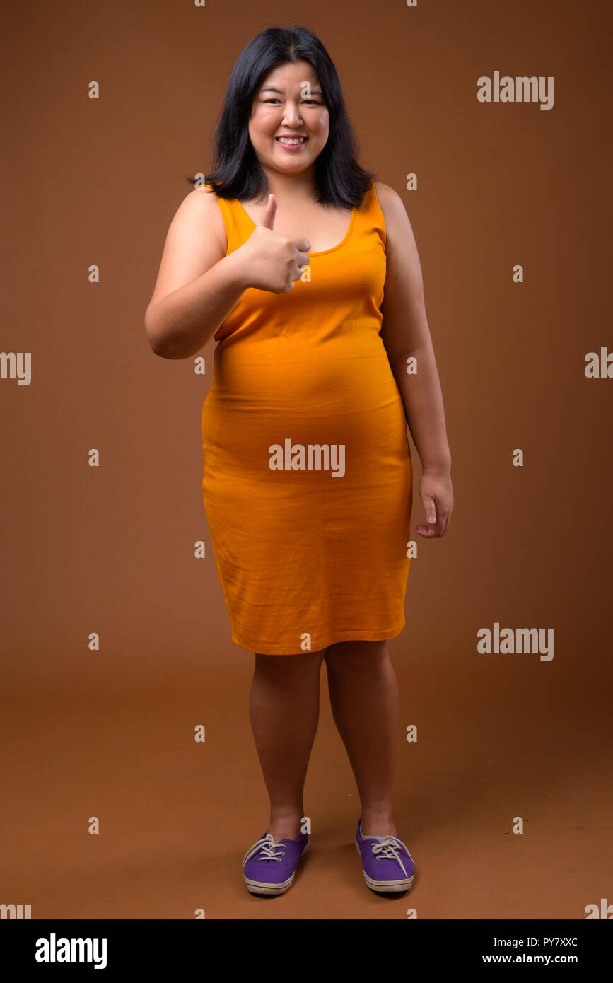 Bellissimo il sovrappeso donna asiatica sorridente e dando pollice in alto Foto Stock