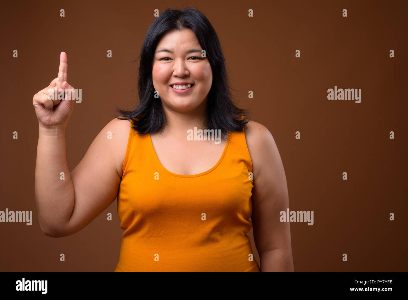 Sorridente sovrappeso donna asiatica puntare il dito fino Foto Stock