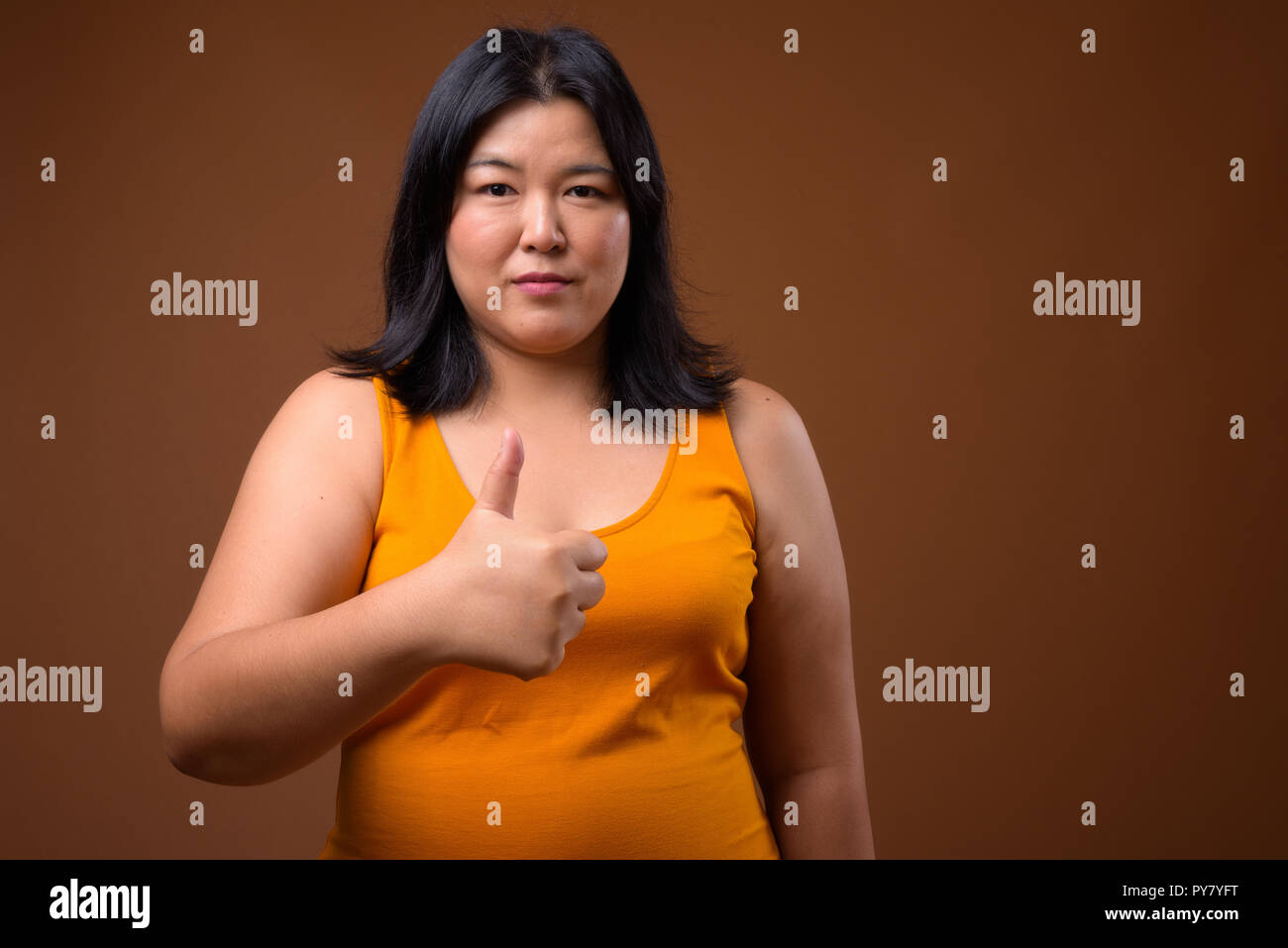 Bellissimo il sovrappeso donna asiatica dando pollice in alto Foto Stock