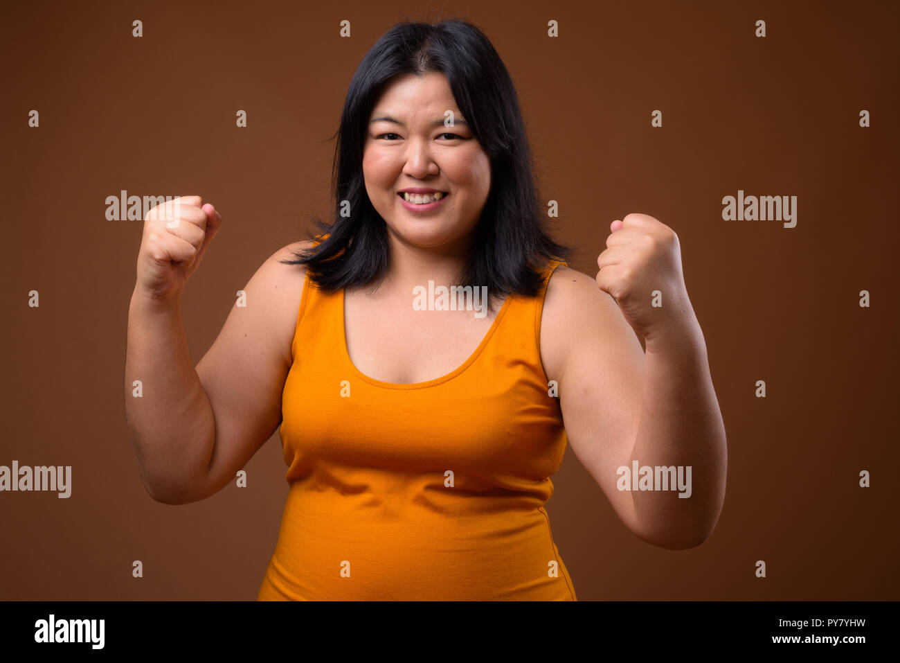 Bella felice sovrappeso donna asiatica a braccia alzate Foto Stock