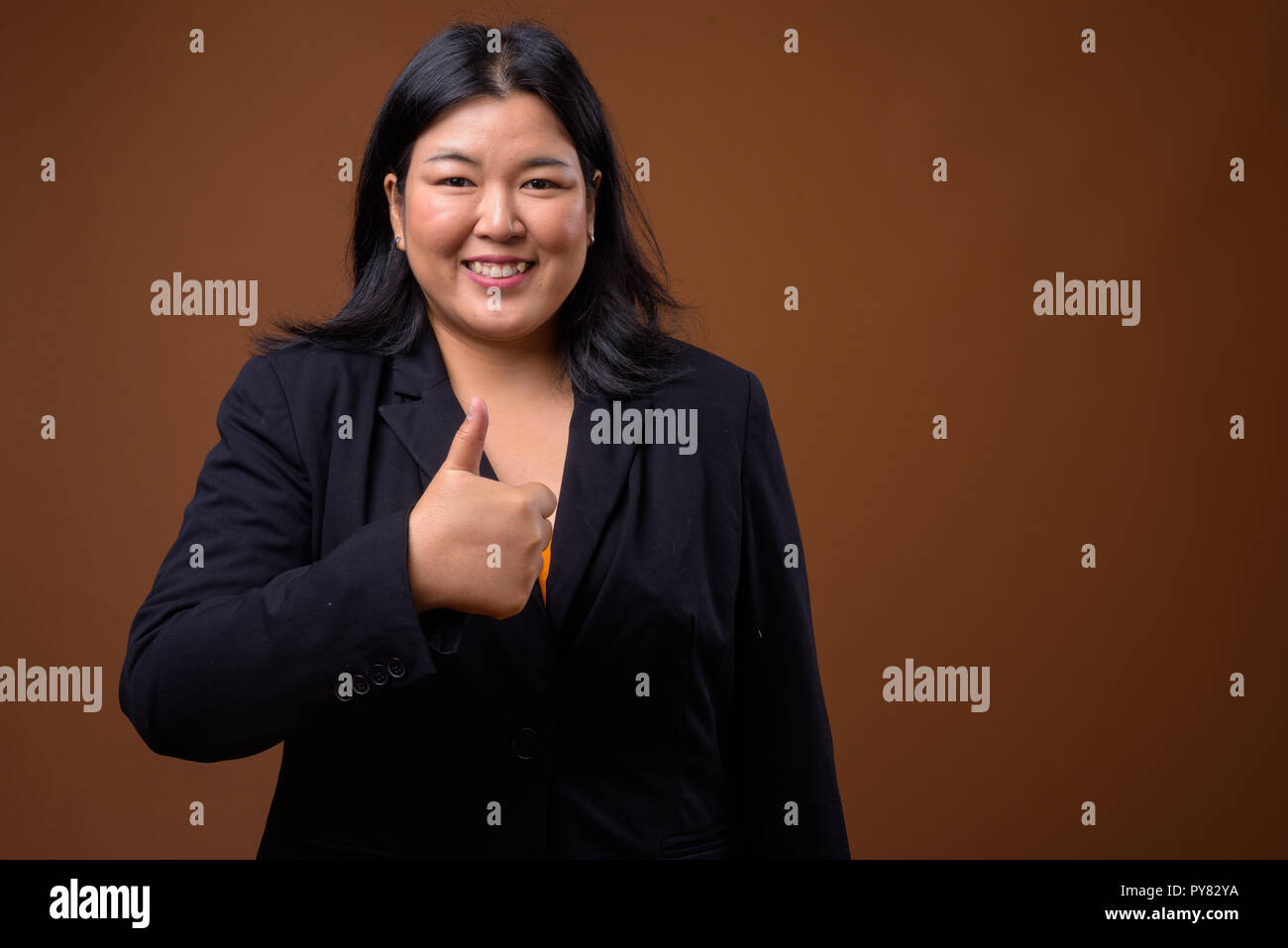 Felice sovrappeso imprenditrice asiatica dando pollice in alto Foto Stock