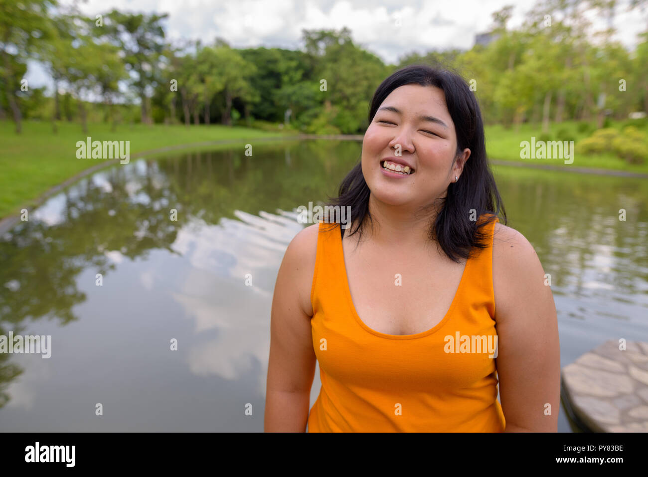 Bellissimo il sovrappeso donna asiatica sorridente con gli occhi chiusi in posizione di parcheggio Foto Stock