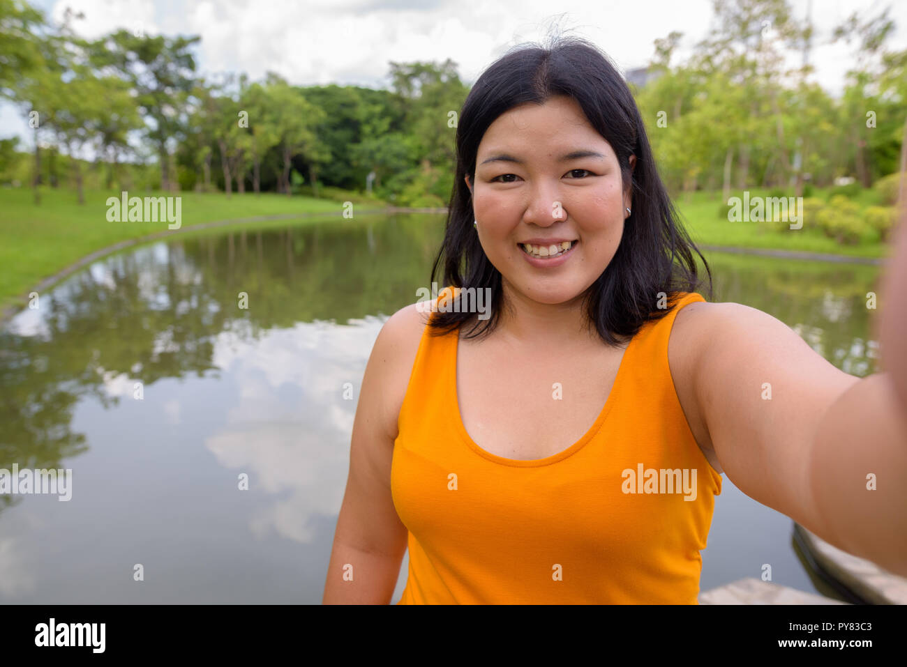 Personale punto di vista di bella donna sovrappeso tenendo selfie in posizione di parcheggio Foto Stock