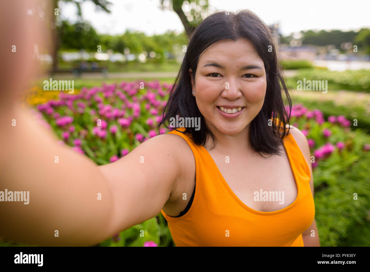 Personale punto di vista di bella donna sovrappeso tenendo selfie in posizione di parcheggio Foto Stock