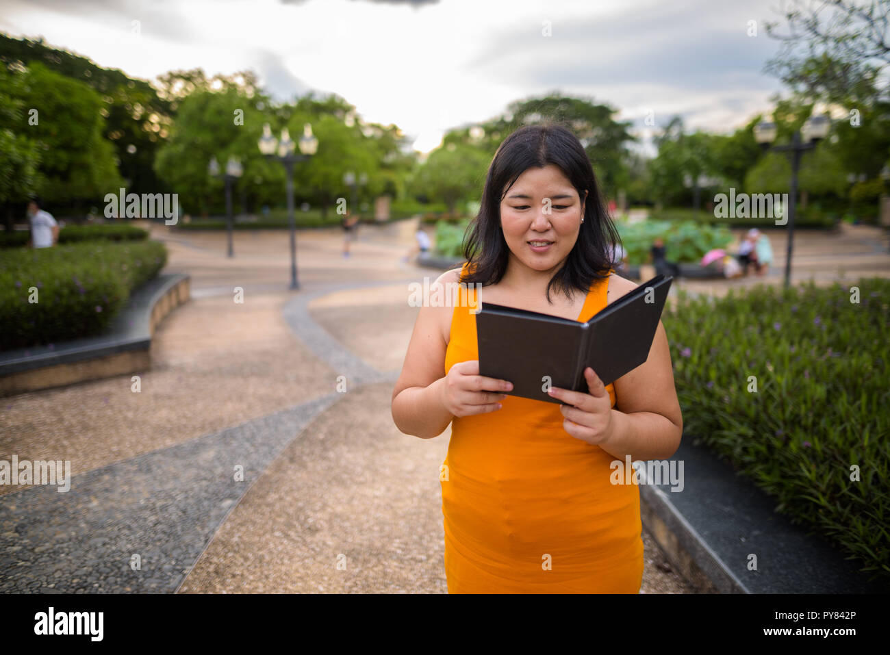 Bellissimo il sovrappeso donna asiatica libro lettura in posizione di parcheggio Foto Stock