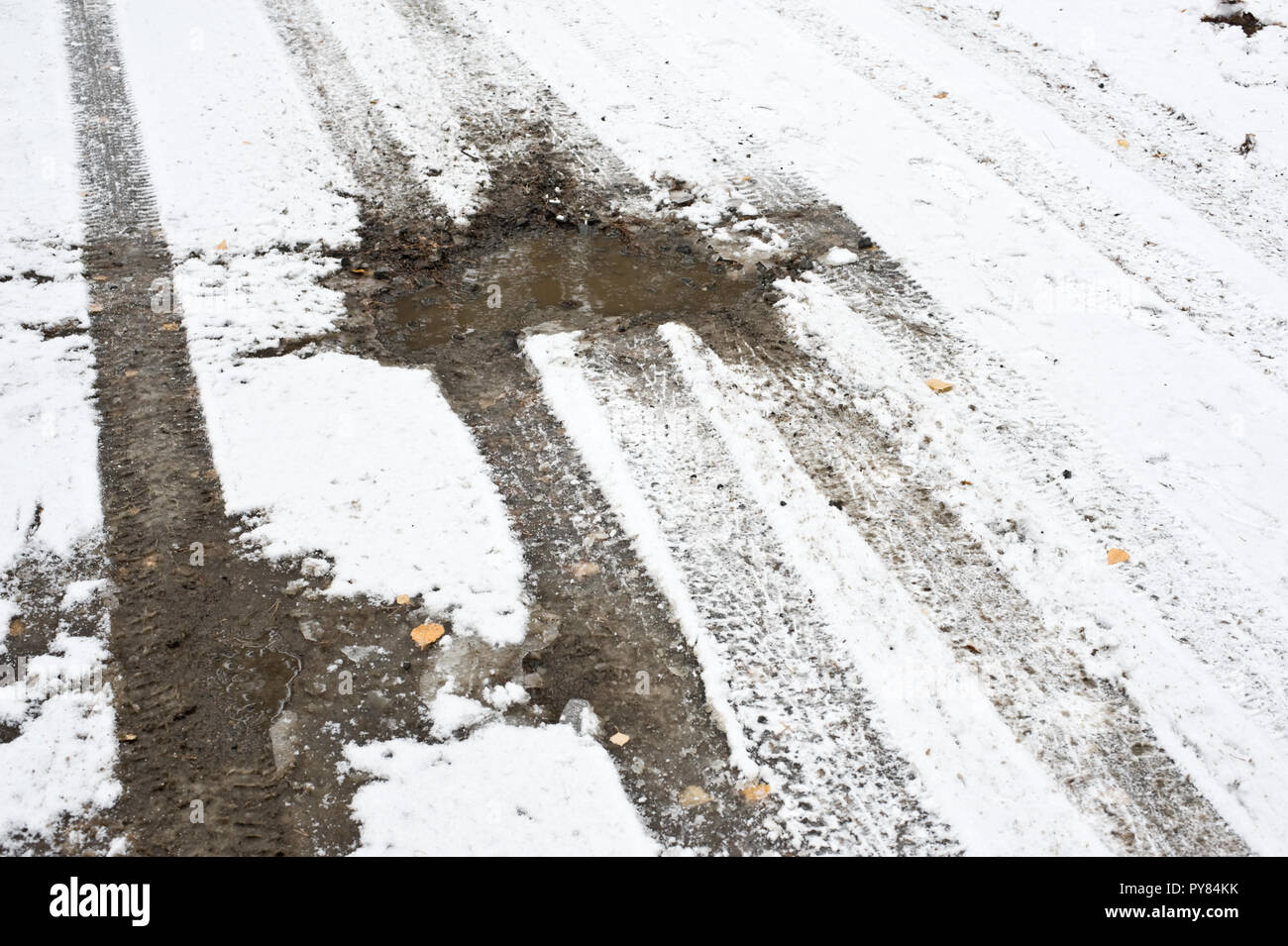 Auto tracce di pneumatico e strada fangosa coperta di neve fresca. Foto Stock