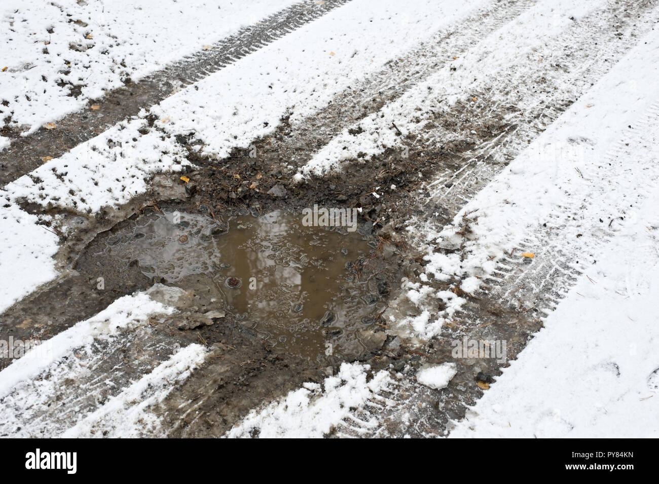 Auto tracce di pneumatico e strada fangosa coperta di neve fresca. Foto Stock