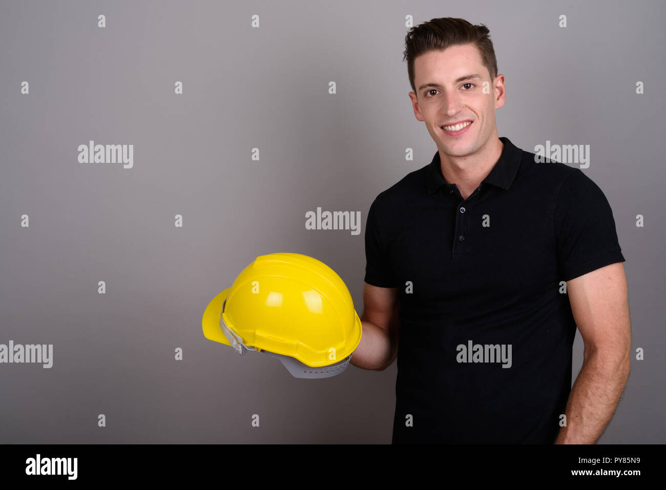 Giovane uomo bello lavoratore edile azienda hardhat Foto Stock