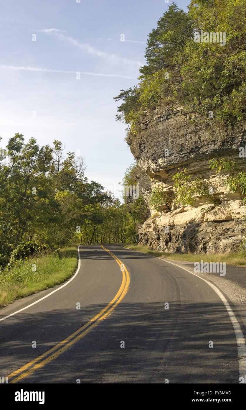 Vista Driver di 2-lane strada curva accanto al grande scogliera di roccia Foto Stock