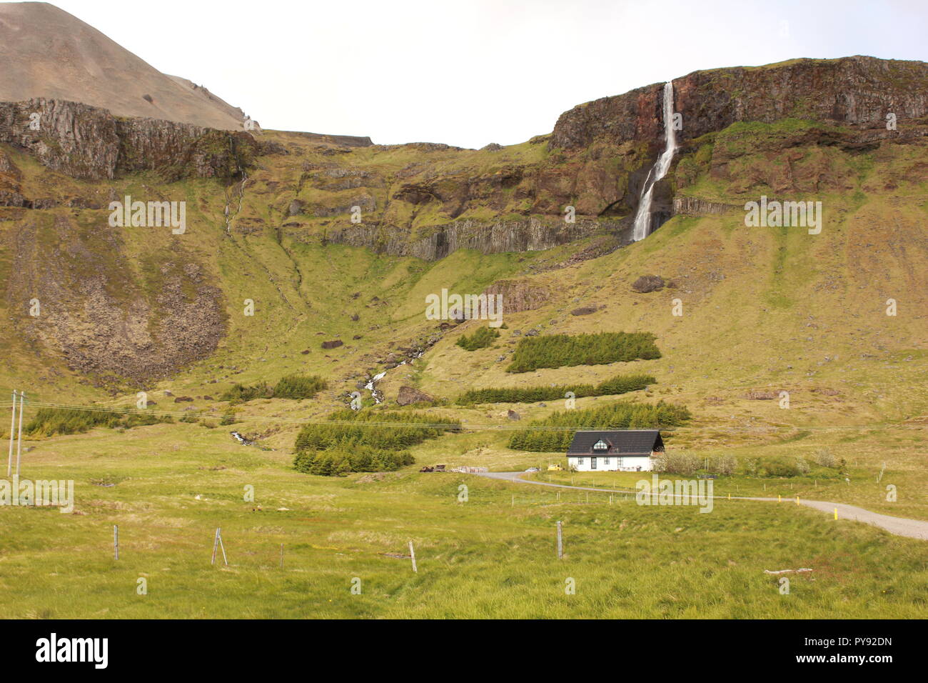 Un paesaggio islandese con una cascata e casa Foto Stock