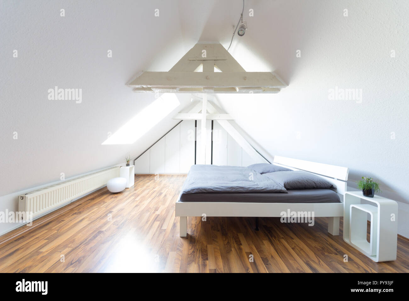 Ampio angolo di visione del moderno e luminoso, puristic mansarda camera da letto con letto matrimoniale e biancheria di colore grigio Foto Stock