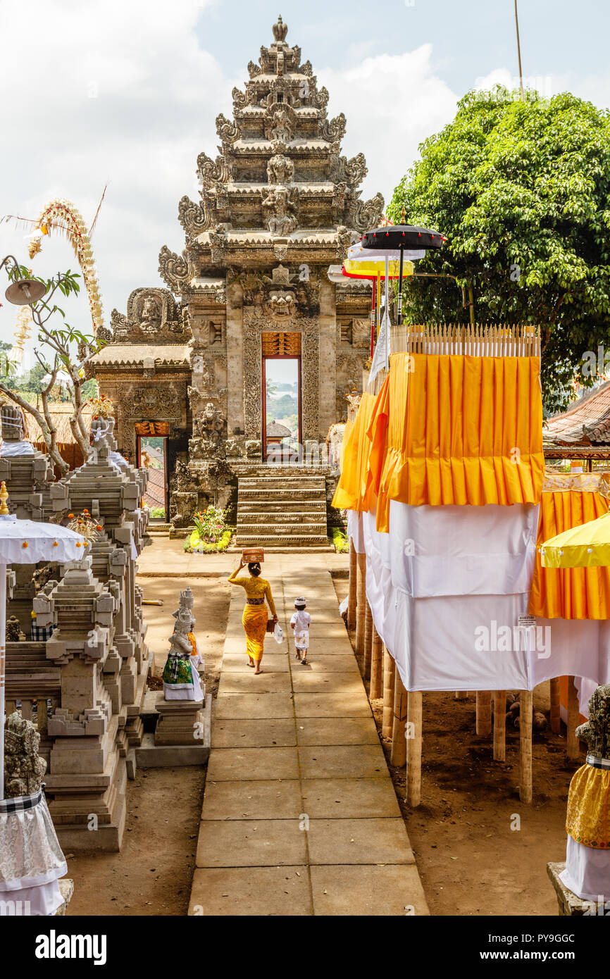 Donna Balinese in kebaya e sarong con keben (scatola per le offerte) e un capretto a pura Kehen, Balinese tempio indù di Bangli Regency, Bali, Indonesia. Foto Stock