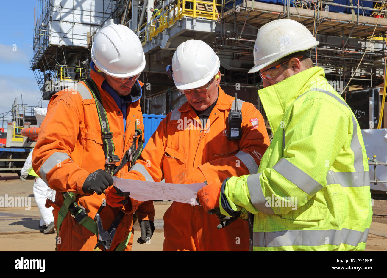 3 ingegneri discus un disegno durante la costruzione di un gas offshore della piattaforma di produzione nel Mare del Nord porto di Hartlepool, Regno Unito Foto Stock