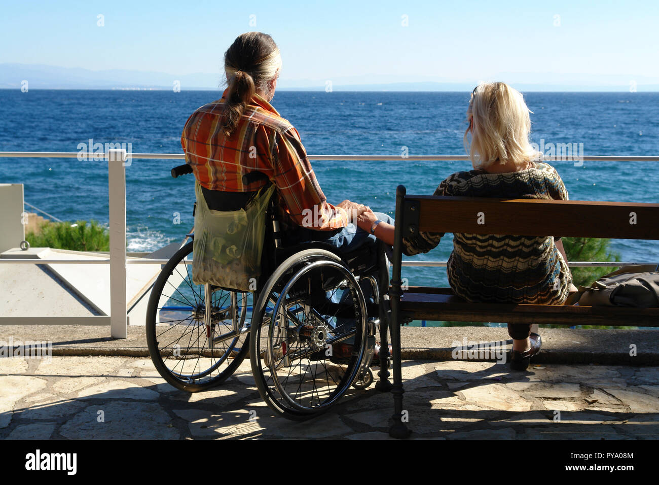 L'uomo im Rollstuhl und seine Frau am Lungomare (strandweg) zwischen Opatija und Lovran Foto Stock